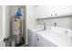 Functional laundry area equipped with washer, dryer, water heater, and white cabinets for storage at 521 Renshaw Ct, Cary, NC 27518