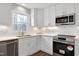 Bright kitchen featuring white cabinets, stainless steel appliances, stone countertops and subway tile backsplash at 5635 Paragon Cir, Durham, NC 27712
