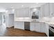 Bright kitchen featuring white cabinets, stainless steel appliances, stone countertops and wood-look flooring at 5635 Paragon Cir, Durham, NC 27712