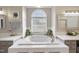 Luxurious bathroom featuring a soaking tub, arched window, and separate vanity area, perfect for relaxation at 6 Kersey Ct, Durham, NC 27713