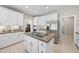 Spacious kitchen with white cabinets, a stainless steel refrigerator, island cooktop, and neutral countertops at 6 Kersey Ct, Durham, NC 27713
