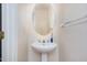 Cozy half bathroom with a pedestal sink and an oval mirror creating a clean look at 9510 Dellbrook Ct, Raleigh, NC 27617