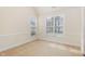 Bright bedroom featuring neutral carpet, two windows, and classic trim details at 9510 Dellbrook Ct, Raleigh, NC 27617
