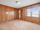 Bedroom with wood paneled walls and carpeted floors, offering a large window for natural light at 9550 Silk Hope Liberty Rd, Siler City, NC 27344