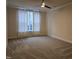 A light-filled bedroom features a ceiling fan, sheer white curtains and neutral carpet at 10420 Sablewood Drive Dr # 102, Raleigh, NC 27617
