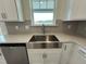 Close-up of a stainless steel farmhouse sink with modern faucet, stainless steel dishwasher and gray subway tile backsplash at 116 Willow Cameron Way, Angier, NC 27501