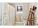 Bathroom featuring a decorative shower curtain, a chrome shelf, white toilet, sink, and a window at 121 Hamilton St, Henderson, NC 27536
