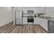 Well-lit kitchen with stainless steel appliances, white cabinets, and wood-look flooring at 2117 Trailside Dr, Durham, NC 27704