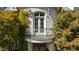 Charming balcony with white french doors surrounded by lush greenery and plants on a brick exterior at 2658 Davis St, Raleigh, NC 27608