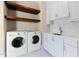 Bright laundry room with wood shelves, white cabinets, sink, and modern machines enhancing home convenience at 2658 Davis St, Raleigh, NC 27608