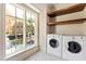 Laundry room features a window, wood shelves, and modern appliances for efficient laundry tasks with exterior views at 2658 Davis St, Raleigh, NC 27608