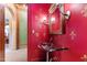 Stylish powder room featuring vibrant red walls with gold accents, a glass sink, and ornate mirror at 2658 Davis St, Raleigh, NC 27608