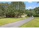 A long driveway and yard leading to a charming yellow house, surrounded by lush greenery and mature trees at 2728 Old Milburnie Rd Rd, Raleigh, NC 27604