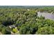 Aerial view of a home surrounded by lush greenery and tall trees, situated near a tranquil lake in the distance at 276 Sagamore Dr, Louisburg, NC 27549