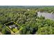 Aerial view of a home with an approximate property line surrounded by tall trees and adjacent to a lake in the distance at 276 Sagamore Dr, Louisburg, NC 27549