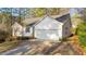 A charming home featuring an attached two-car garage, manicured shrubs, and a dark paved driveway in a natural setting at 276 Sagamore Dr, Louisburg, NC 27549