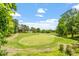 Beautiful golf course view with lush green grass, trees, and blue skies and a glimpse of nearby houses at 3025 Osterley St, Raleigh, NC 27614