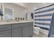 Bathroom vanity with gray cabinets, granite countertop, and blue striped shower curtain at 3512 Dragonfly River Ct, Raleigh, NC 27604