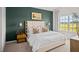 Stylish bedroom showcasing a luxurious bed, sconce lighting, dark green walls, and a view of the outdoor landscape at 369 Swift Creek Farm Ln, Clayton, NC 27520