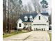 Charming two-story home with white siding, black roof, three-car garage, and beautifully landscaped front yard at 564 Woodbridge Ct, Wake Forest, NC 27587