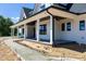 A covered front porch that offers a relaxing outdoor space, framed by elegant white columns and black trim at 6509 Zebulon Rd, Wake Forest, NC 27587