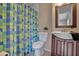 This bathroom has a vanity, a toilet with plant decor and a shower with a blue and green curtain at 7712 Falcon Rest Cir, Raleigh, NC 27615