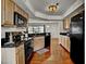 Bright kitchen with wood cabinets, black appliances, granite counters, and wood flooring at 7712 Falcon Rest Cir, Raleigh, NC 27615