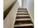 A staircase with dark stained wooden treads and white risers leads upstairs, complemented by a wooden handrail at 79 Willow Cameron Way, Angier, NC 27501
