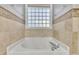 Close up of soaking tub surrounded by tile and natural light from window at 8116 Hartwood Glen Cir, Willow Springs, NC 27592