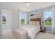 Well-appointed bedroom with a patterned accent wall, bench, and a view of the green outdoors at 98 Willow Cameron Way, Angier, NC 27501