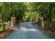 Gated gravel driveway with two lanterns sitting atop stone pillars at 1018 Terrell Woods Ln, Chapel Hill, NC 27516