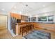 Modern kitchen featuring wood cabinetry, stainless steel appliances, and a cozy breakfast bar with seating, bathed in natural light at 1018 Terrell Woods Ln, Chapel Hill, NC 27516
