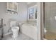 Bright bathroom features a white vanity, toilet, a soaking tub under the window and glass shower at 1721 Kingston Heath Way, Raleigh, NC 27604