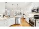 A white kitchen with a large island, stainless steel appliances, and a view to the backyard at 19 Juneberry Pl, Clayton, NC 27527