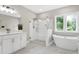 A bright bathroom with a walk-in shower, standalone tub, and double vanities, designed for relaxation and comfort at 213 W Weatherford Dr, Angier, NC 27501