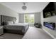 A bright bedroom features a tufted headboard bed, modern fireplace, ceiling fan, and neutral tones for a tranquil feel at 213 W Weatherford Dr, Angier, NC 27501