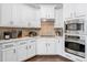 Well-designed kitchen with stainless steel appliances, white cabinets, tile backsplash, and hardwood floors at 4270 Aviemore Run, Burlington, NC 27215
