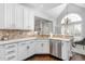 Bright kitchen with white cabinets, stainless steel dishwasher, and pass through to the dining room with large window at 4270 Aviemore Run, Burlington, NC 27215