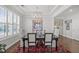 Formal dining area featuring a stylish chandelier, dark table set and bright light from the shuttered window at 516 Ivy Arbor Way, Holly Springs, NC 27540