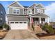 Charming two-story home with gray siding, stone accents, an American flag, and a two-car garage at 516 Ivy Arbor Way, Holly Springs, NC 27540