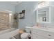 Bright bathroom featuring a glass-enclosed shower/tub combo, modern fixtures and stylish decor at 610 Brownstone Rd, Gibsonville, NC 27249