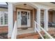 Inviting porch with brick columns, white railings, and a welcoming 'hello' mat at the front door at 610 Brownstone Rd, Gibsonville, NC 27249