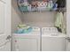 Bright laundry room with front loading machines and storage shelves for organizing cleaning supplies at 610 Brownstone Rd, Gibsonville, NC 27249