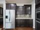 Kitchen with stainless steel refrigerator and oven, dark cabinets, mosaic backsplash, and granite countertops at 800 Tree Green Ln, Wake Forest, NC 27587