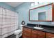 Bright bathroom featuring wood vanity with black counter, tile floors, a toilet, and shower with striped shower curtain at 1002 Pleasant Dr, Mebane, NC 27302