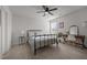 Bright bedroom with a black metal bed, desk, and a ceiling fan fixture and carpet flooring at 1020 Broadlands Way, Graham, NC 27253