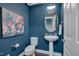 Stylish half bathroom with a pedestal sink, decorative mirror, and elegant blue wall paint at 10510 Sablewood Dr # 114, Raleigh, NC 27617