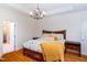 Bright bedroom featuring a queen bed, hardwood floors, chandelier, and access to the closet at 10620 Staghound Trl, Zebulon, NC 27597