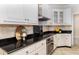 Modern kitchen with white cabinets, black granite countertops, and stainless steel appliances at 10620 Staghound Trl, Zebulon, NC 27597