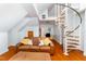 Spacious living room with hardwood floors, cozy seating, and spiral staircase access at 10620 Staghound Trl, Zebulon, NC 27597